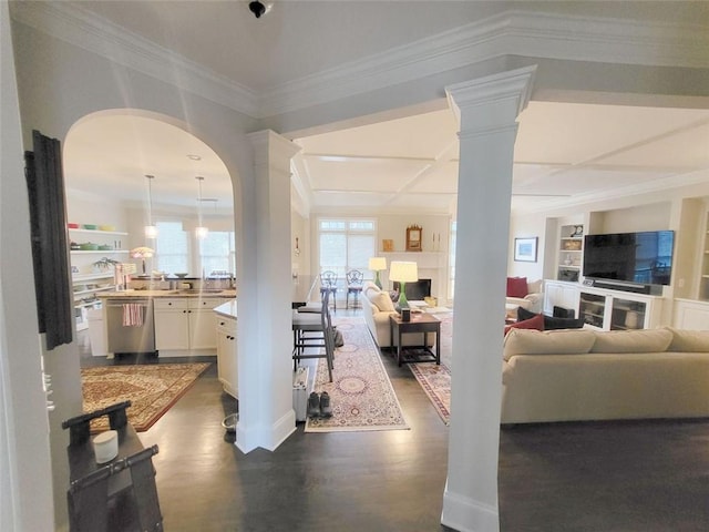 living room featuring built in features, baseboards, crown molding, and ornate columns