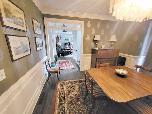 dining space featuring wallpapered walls, wood finished floors, wainscoting, a decorative wall, and crown molding