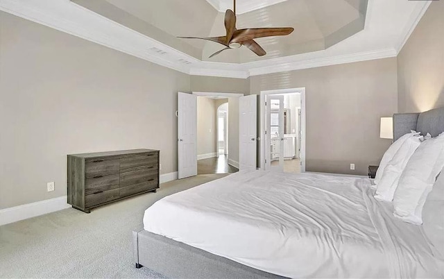 carpeted bedroom featuring a tray ceiling, baseboards, ensuite bathroom, and ornamental molding