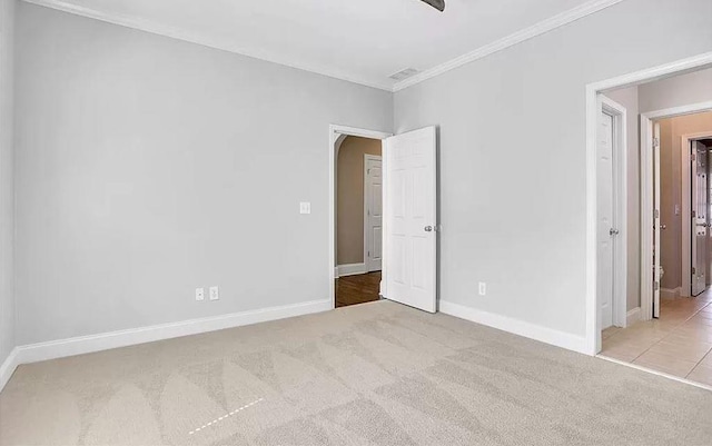 unfurnished bedroom featuring visible vents, crown molding, baseboards, carpet, and arched walkways