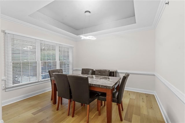 dining area featuring a raised ceiling, crown molding, and light hardwood / wood-style floors