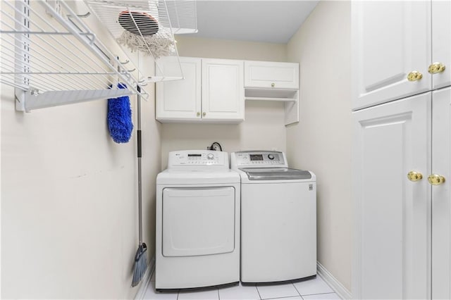 laundry area with light tile patterned floors, washer and clothes dryer, and cabinets