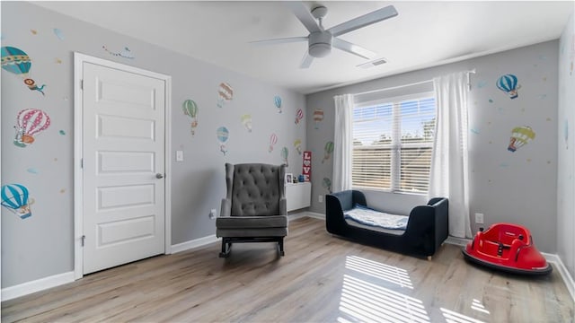 living area with ceiling fan and light hardwood / wood-style floors