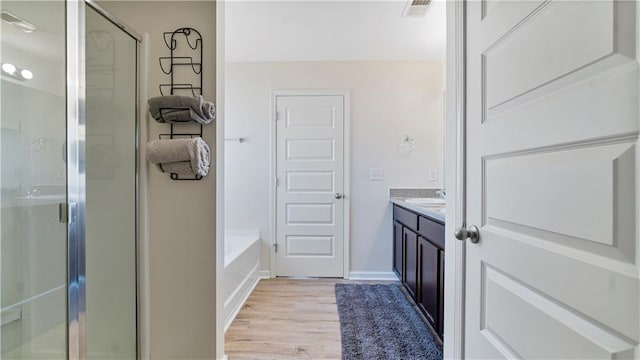 bathroom featuring vanity, hardwood / wood-style floors, and plus walk in shower