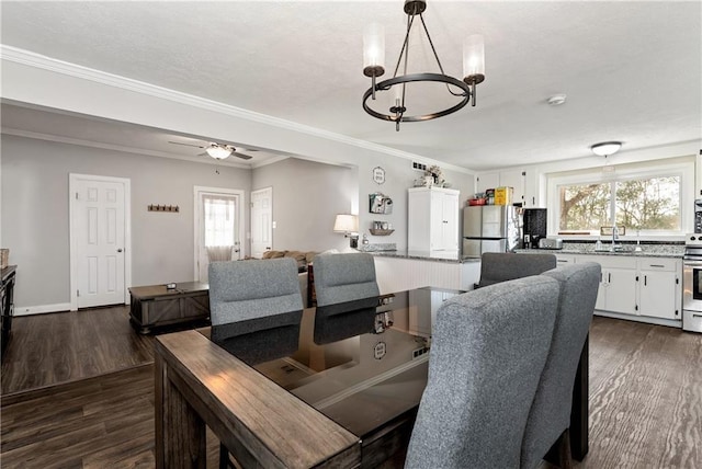 dining room with dark wood finished floors, crown molding, ceiling fan with notable chandelier, and a healthy amount of sunlight