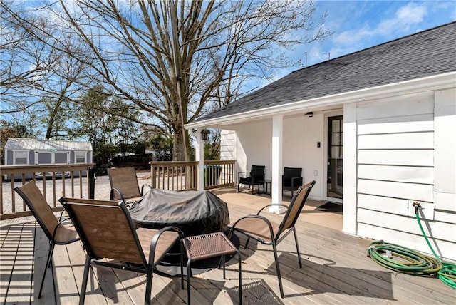 deck featuring an outdoor structure, outdoor dining space, and a storage shed