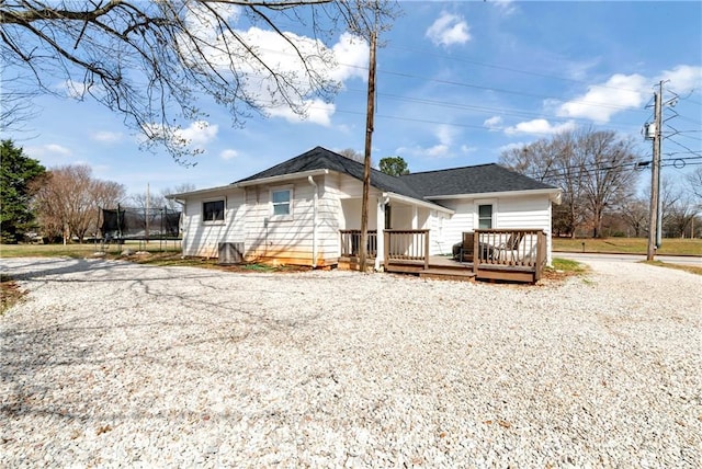 view of front of home with a deck, gravel driveway, and a trampoline