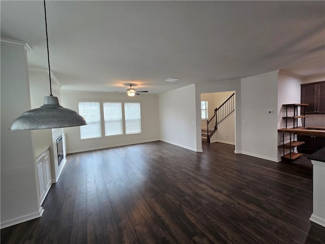 5521 Shallow Branch Dr, Flowery Branch, GA 30542 - unfurnished living room with stairway, healthy amount of natural light, dark wood-style flooring, ceiling fan, and crown molding