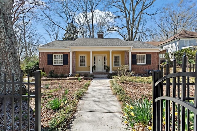 view of front of property with a fenced front yard, brick siding, covered porch, and a chimney