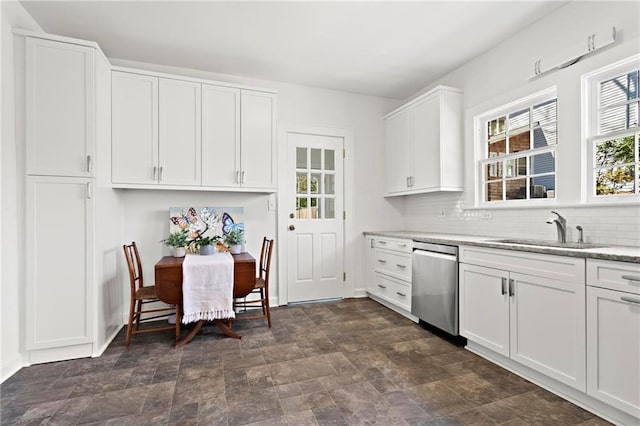 kitchen with decorative backsplash, white cabinets, dishwasher, and a sink