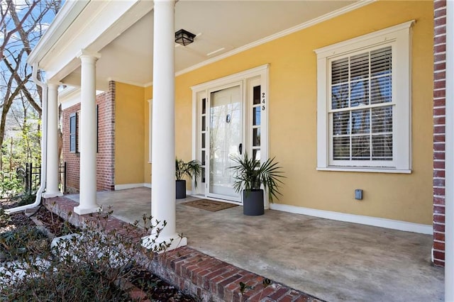 view of exterior entry with stucco siding, brick siding, and a porch