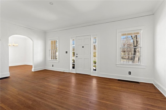 foyer entrance with baseboards, arched walkways, wood finished floors, and crown molding