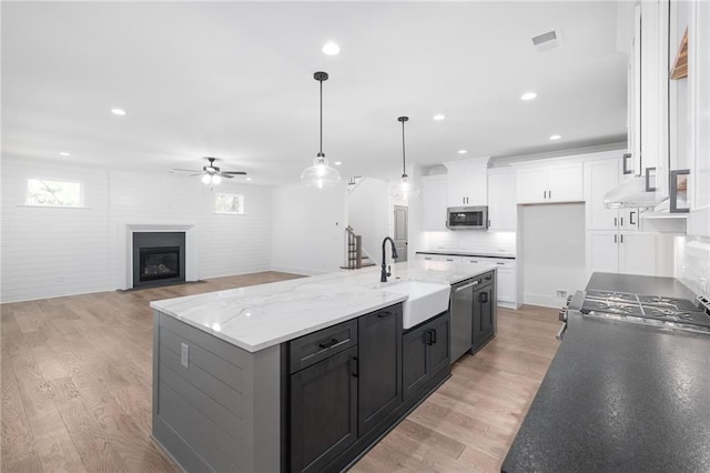 kitchen featuring a spacious island, sink, white cabinetry, light wood-type flooring, and appliances with stainless steel finishes