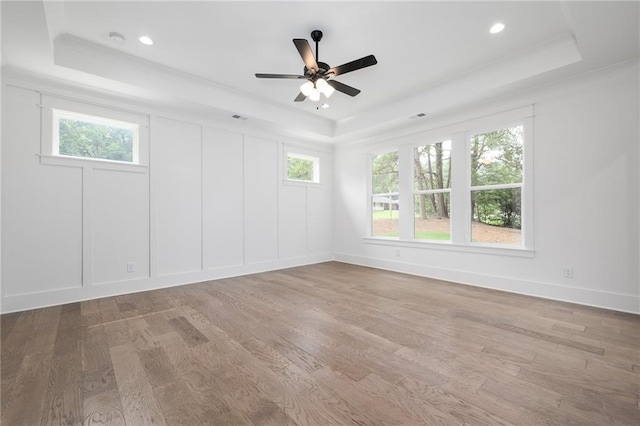 unfurnished room with a tray ceiling, light hardwood / wood-style floors, and ceiling fan