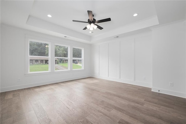 empty room featuring hardwood / wood-style flooring, a raised ceiling, and ceiling fan