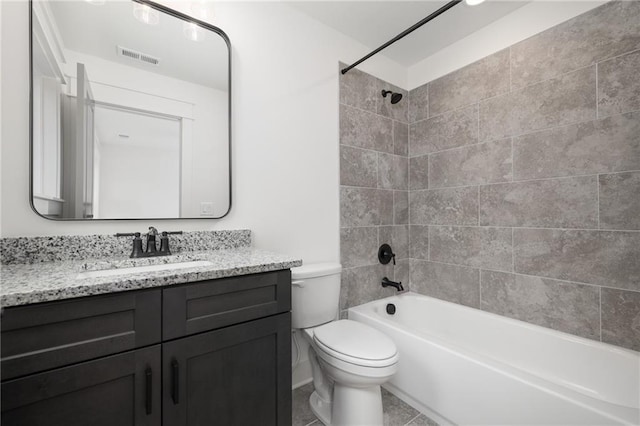 full bathroom featuring toilet, tiled shower / bath combo, vanity, and tile patterned flooring