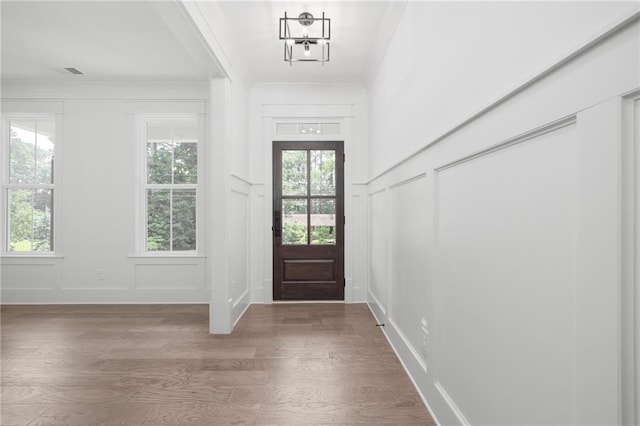 entrance foyer with hardwood / wood-style flooring, ornamental molding, and a chandelier