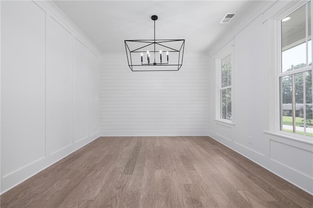 unfurnished dining area featuring light hardwood / wood-style floors, a notable chandelier, and a wealth of natural light