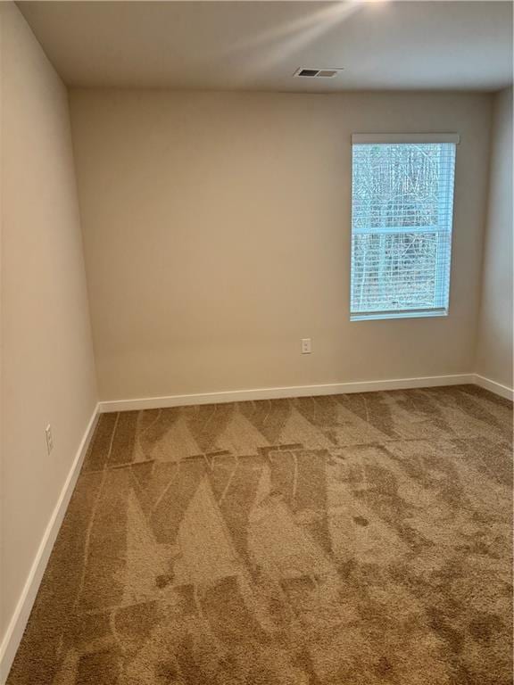 spare room featuring carpet, visible vents, and baseboards