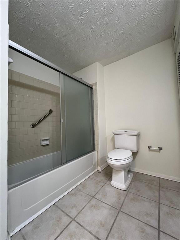 bathroom featuring tile patterned floors, shower / bath combination with glass door, a textured ceiling, and toilet