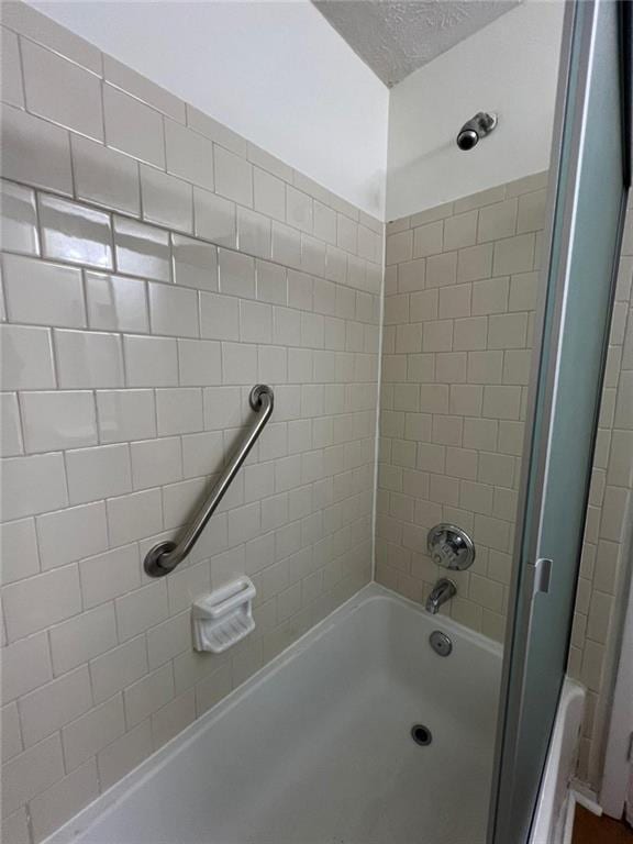 bathroom with tiled shower / bath combo and a textured ceiling