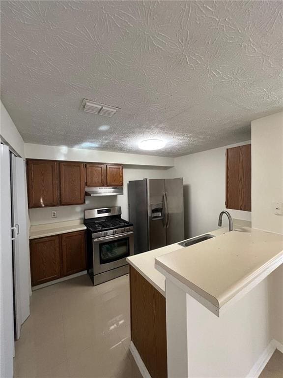 kitchen featuring kitchen peninsula, appliances with stainless steel finishes, a kitchen bar, a textured ceiling, and sink