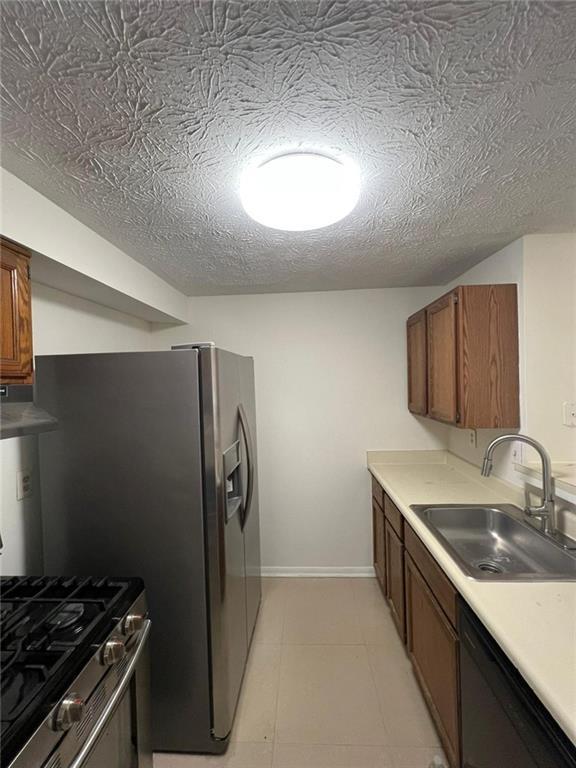 kitchen featuring range hood, sink, stainless steel appliances, and a textured ceiling