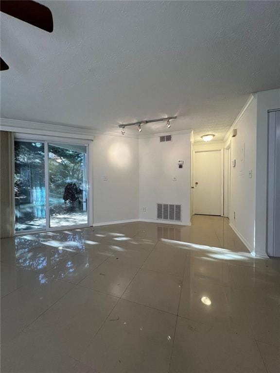 empty room with crown molding, tile patterned flooring, rail lighting, and a textured ceiling