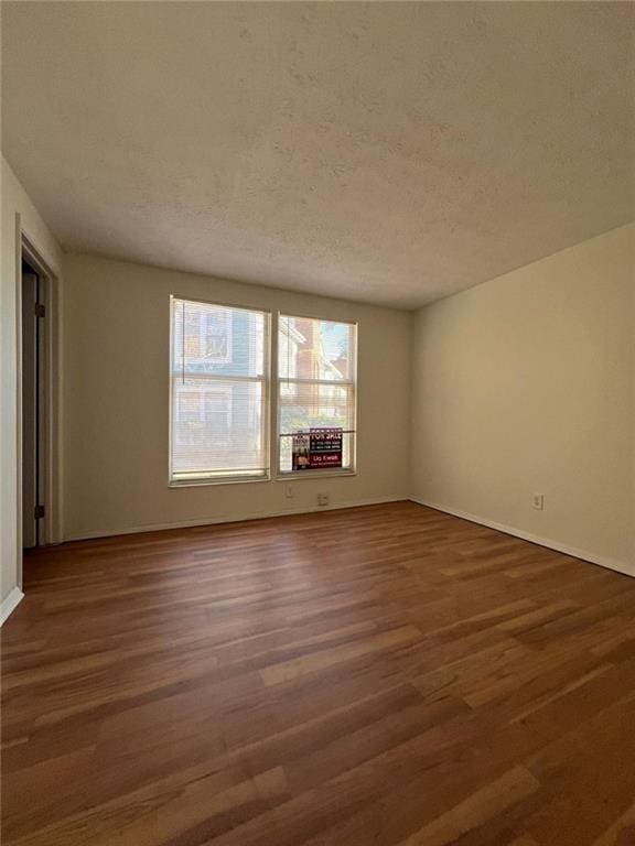 spare room featuring dark hardwood / wood-style flooring and a textured ceiling