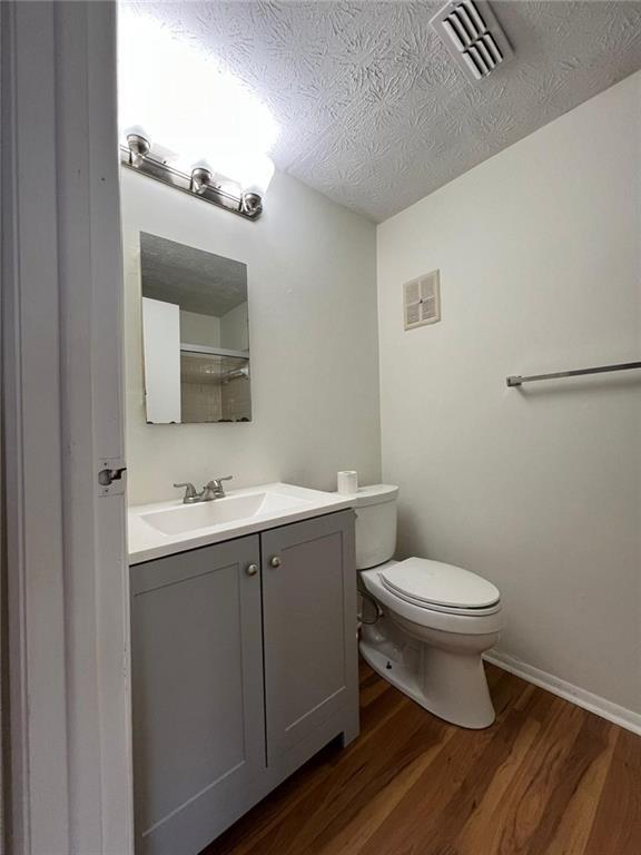 bathroom featuring toilet, vanity, a textured ceiling, and hardwood / wood-style flooring