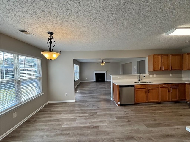 kitchen with sink, dishwasher, pendant lighting, a textured ceiling, and light hardwood / wood-style floors