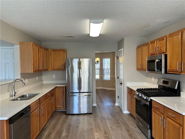 kitchen featuring a textured ceiling, stainless steel appliances, hardwood / wood-style flooring, and sink