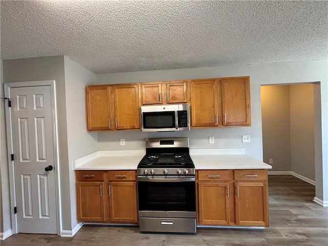 kitchen featuring a textured ceiling, wood-type flooring, and stainless steel appliances