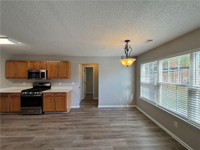 kitchen featuring pendant lighting, a textured ceiling, stainless steel appliances, and light hardwood / wood-style flooring