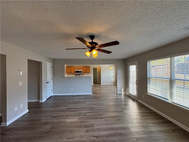 unfurnished living room with dark hardwood / wood-style floors, ceiling fan, and a textured ceiling