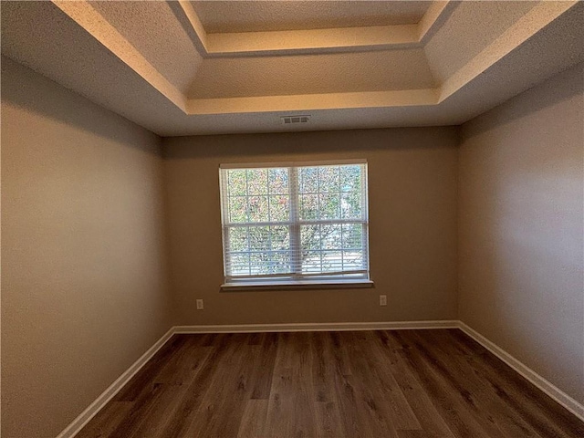 spare room with a tray ceiling and dark hardwood / wood-style floors