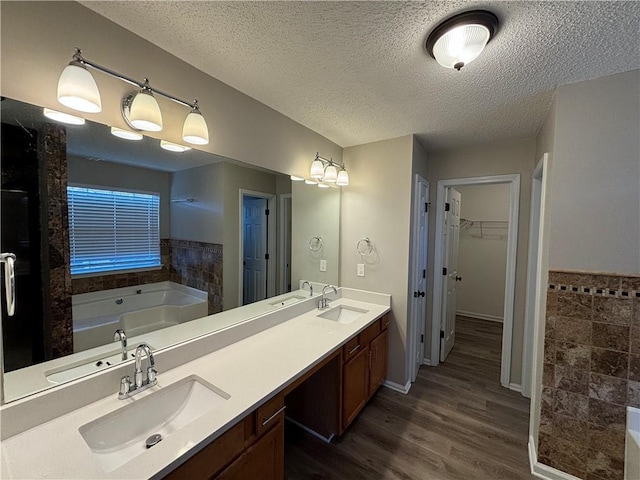 bathroom featuring a bathing tub, vanity, wood-type flooring, and a textured ceiling