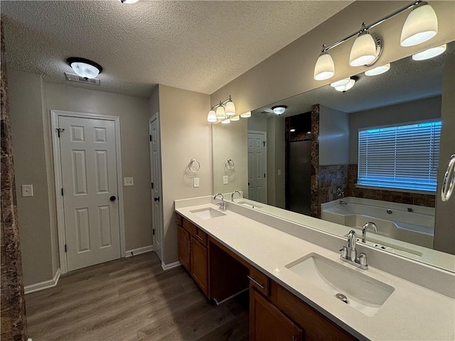 bathroom with a bathing tub, vanity, wood-type flooring, and a textured ceiling