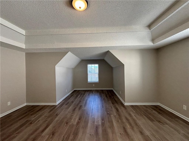 bonus room with a textured ceiling, dark hardwood / wood-style flooring, and lofted ceiling