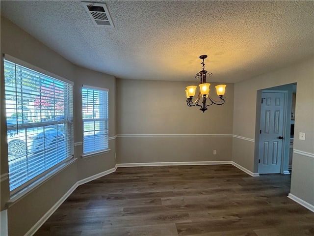 unfurnished room with a textured ceiling, a chandelier, and dark hardwood / wood-style floors