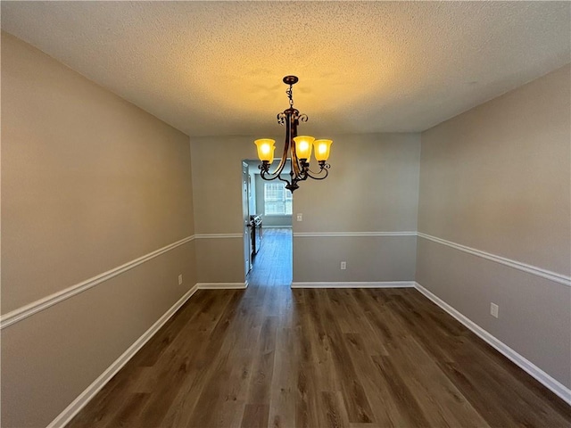 unfurnished dining area with a chandelier, a textured ceiling, and dark hardwood / wood-style floors