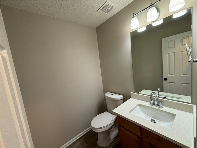 bathroom with vanity, toilet, wood-type flooring, and a textured ceiling