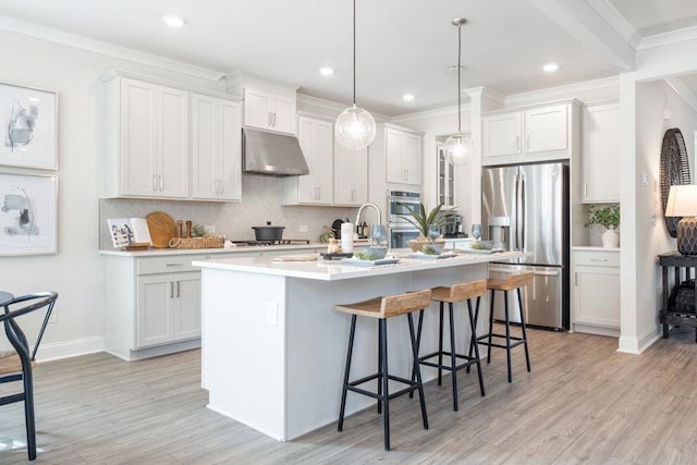 5315 Trescott Path, Cumming, GA 30028 - kitchen with stainless steel appliances, under cabinet range hood, backsplash, light wood-style flooring, and a kitchen island with sink
