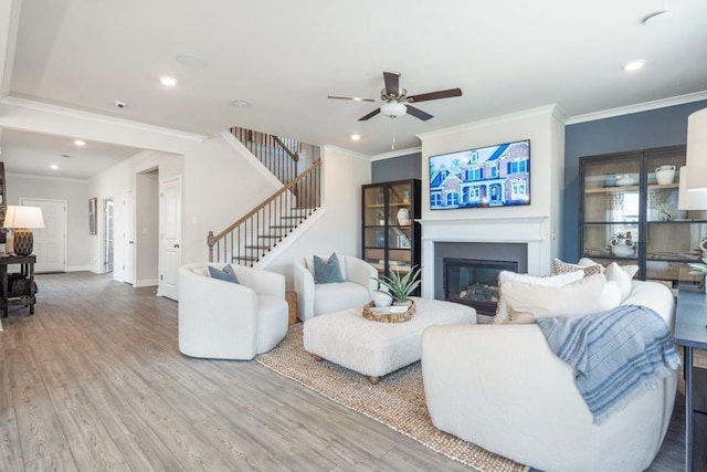 5315 Trescott Path, Cumming, GA 30028 - living area featuring stairway, a glass covered fireplace, wood finished floors, ornamental molding, and ceiling fan