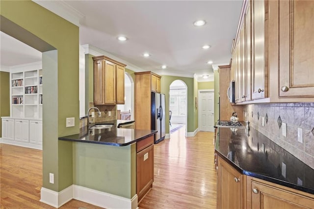 1605 Pavillion Ridge Dr SE, Smyrna, GA 30080 - kitchen with stainless steel appliances, ornamental molding, light wood-style floors, tasteful backsplash, and arched walkways
