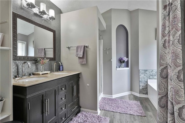 bathroom featuring a chandelier, decorative backsplash, hardwood / wood-style flooring, vanity, and a bath