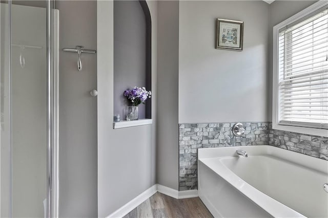 bathroom with a washtub, hardwood / wood-style floors, and a healthy amount of sunlight