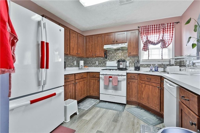 kitchen with white appliances, a textured ceiling, light hardwood / wood-style flooring, and backsplash