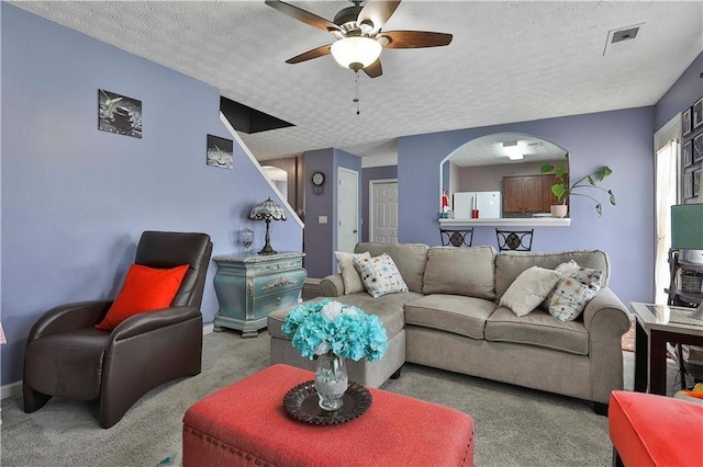 living room featuring light carpet, ceiling fan, and a textured ceiling