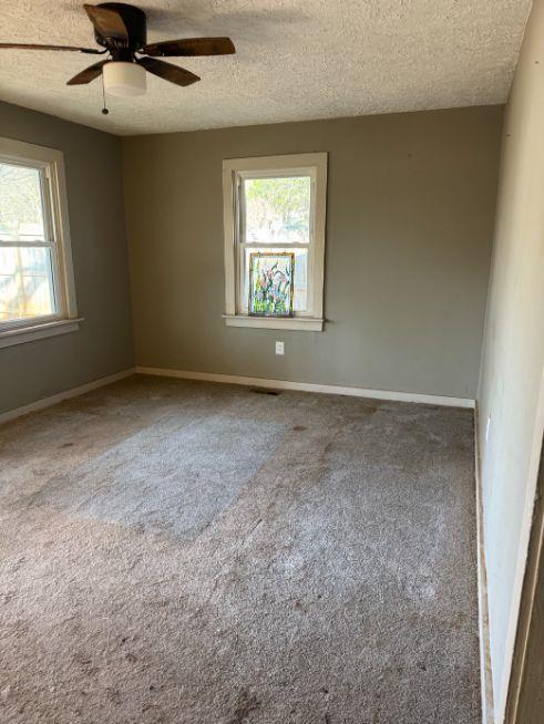 empty room with ceiling fan, carpet flooring, and a textured ceiling